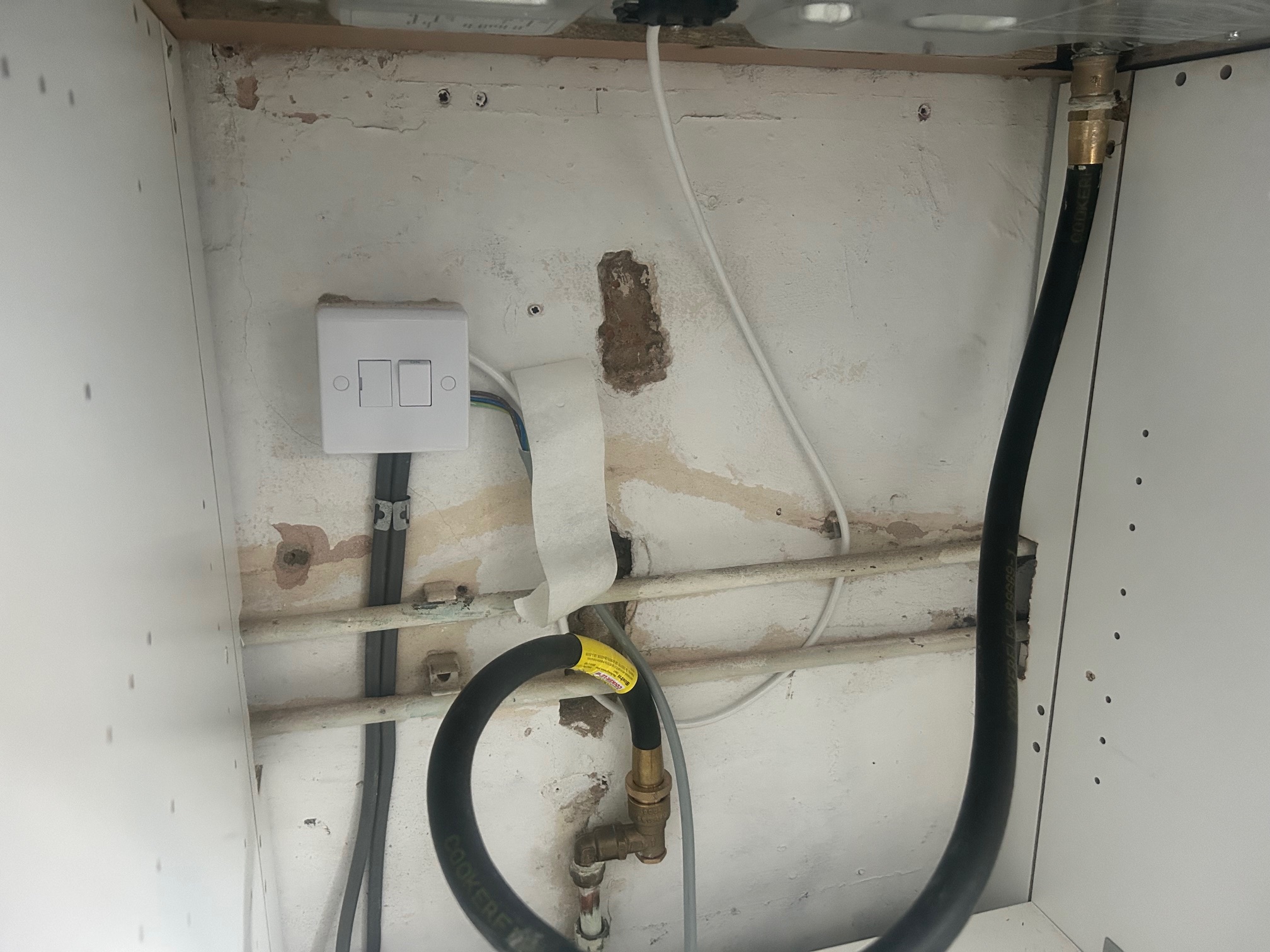Non-compliant black flexible cooker hose improperly connected to a gas hob in Grimsby (DN32)
